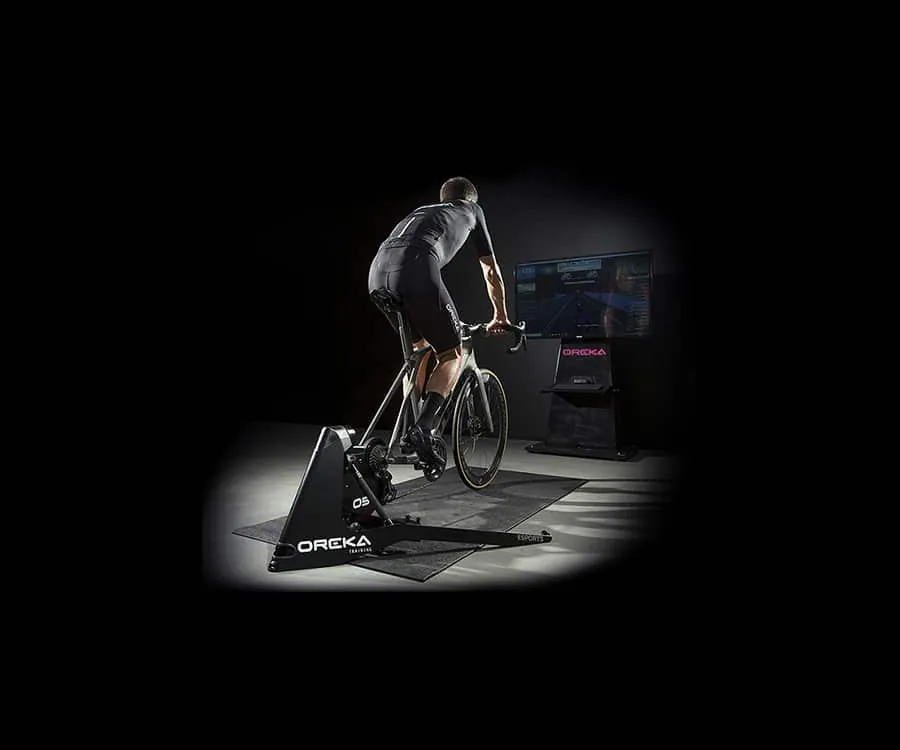 Cyclist training on an OREKA indoor trainer in a dark studio